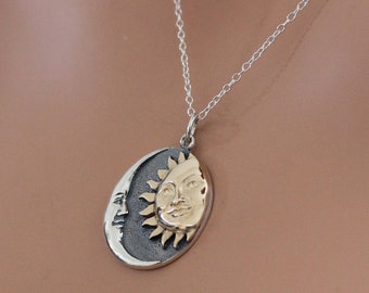May include: A silver chain necklace with a pendant featuring a gold sun and a silver crescent moon.