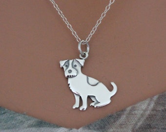 May include: A silver dog pendant necklace. The pendant depicts a dog with a white body, a dark spot, and a dark head with white markings. The chain is a fine silver chain.