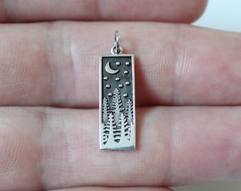 Puede incluir: Encanto de colgante de plata con una silueta detallada de un bosque con una luna creciente y estrellas.