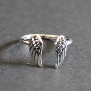 Op de afbeelding: Een zilveren ring met twee engelenvleugels op de band.