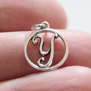 May include: Silver charm with a cursive letter Y in a circle.