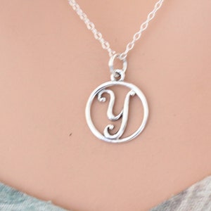 May include: A silver necklace with a pendant featuring the letter Y in a circle.