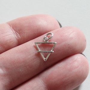 May include: A silver charm in the shape of a triangle with a line across the middle. The charm is a symbol of water.