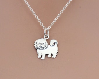 May include: A silver necklace with a small, detailed charm of a Shih Tzu dog.