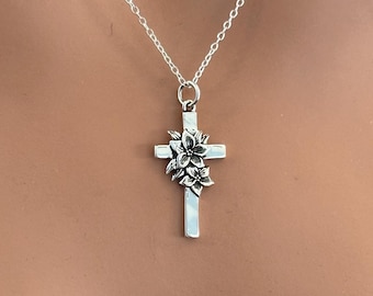May include: A silver chain necklace with a silver cross pendant featuring a floral design.