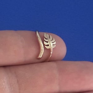 Op de afbeelding: Een verstelbare ring met een bladontwerp in een gouden tint. De ring is open en kan worden aangepast aan verschillende vingermaten.