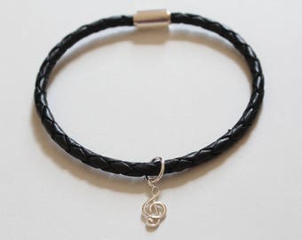 Peut inclure: Un bracelet en cuir noir avec un charme de clé de sol argenté.
