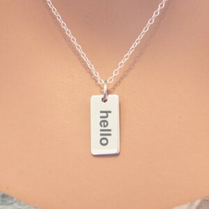 May include: A silver necklace with a rectangular pendant that says "hello" on it.
