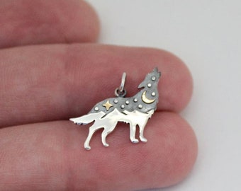 Könnte beinhalten: Ein silberner Wolfsanhänger mit Mond- und Sternenmotiv. Der Wolf heult zum Mond und die Sterne sind über seinen Körper verstreut.