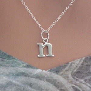 May include: A silver chain necklace with a silver letter 'n' pendant.