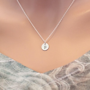 May include: A silver chain necklace with a small, round pendant featuring the letter "P" engraved on it.