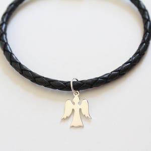 Puede incluir: Un brazalete trenzado de cuero negro con un dije de &aacute;ngel de plata.