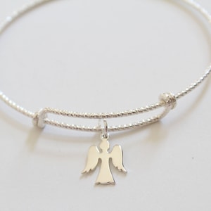 Puede incluir: Un brazalete de plata con un delicado dije de &aacute;ngel. El brazalete est&aacute; hecho de alambre trenzado y tiene un cierre simple.