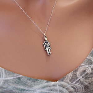 May include: A silver necklace with a detailed nutcracker pendant.