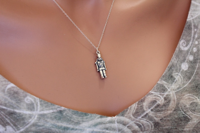 May include: A silver necklace with a detailed nutcracker pendant.