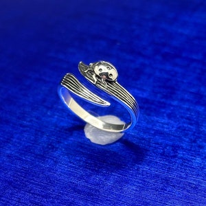 May include: A silver ring with a ladybug design. The ring is open and adjustable.