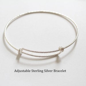 May include: A silver adjustable bangle bracelet with a twisted design.