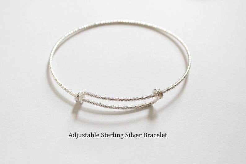 May include: A silver adjustable bangle bracelet with a twisted design.