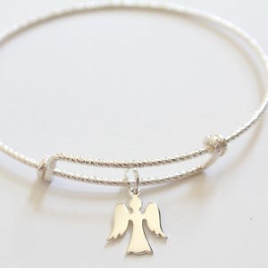 Puede incluir: Un brazalete de plata con un delicado dije de &aacute;ngel. El brazalete est&aacute; hecho de alambre trenzado y tiene un cierre simple.