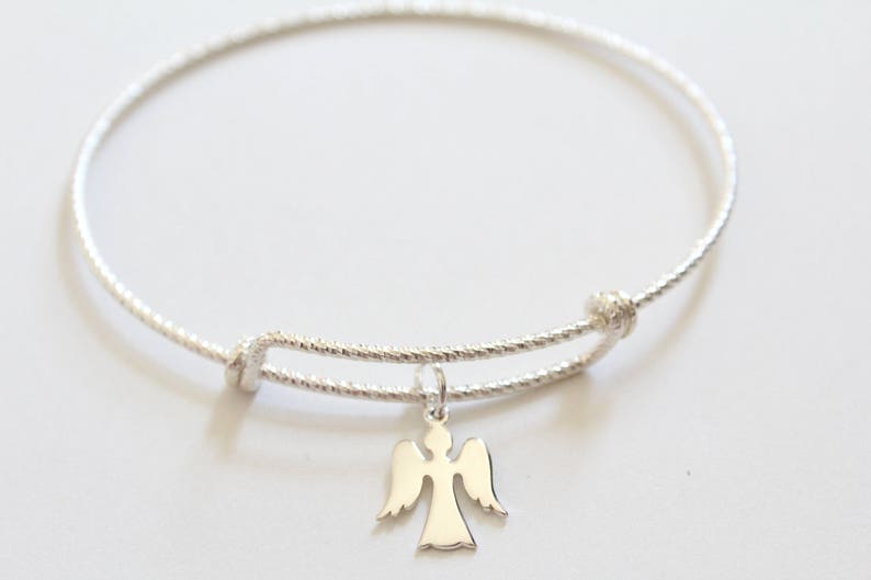 Puede incluir: Un brazalete de plata con un delicado dije de &aacute;ngel. El brazalete est&aacute; hecho de alambre trenzado y tiene un cierre simple.