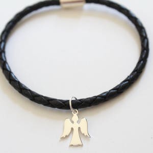 Puede incluir: Un brazalete de cuero trenzado negro con un dije de &aacute;ngel de plata.
