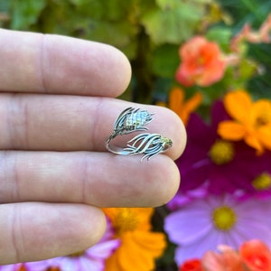 May include: A silver ring with a detailed design of a wheat stalk and a wheat head. The ring is adjustable and can be worn on any finger.