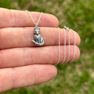 Op de afbeelding: Een zilveren vos-hangerketting met een delicate ketting. De vos zit met zijn staart om zijn lichaam gewikkeld.