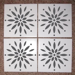 May include: Four white ceramic tiles with a gray floral design. Each tile features a stylized flower with a circular center and radiating petals.