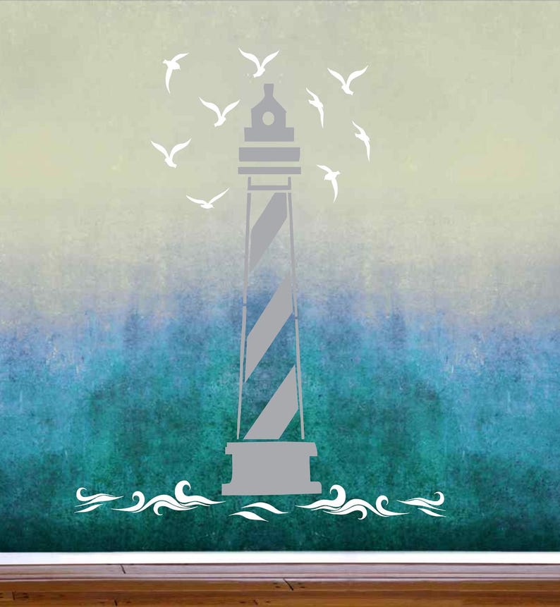 May include: A wall decal featuring a gray lighthouse with diagonal stripes, surrounded by white silhouettes of flying seagulls. The design includes stylized white waves at the base of the lighthouse, set against a gradient background transitioning from light yellow to deep blue.