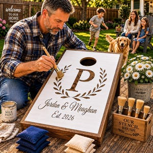 May include: A wooden cornhole board with a white surface featuring a dark wood grain letter P inside a laurel wreath, the names Jordan & Meaghan, and the text Est. 2026. The board includes a circular hole and a dark wood frame on a table.
