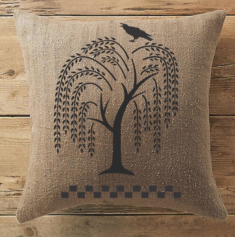 May include: A brown burlap pillow with a black silhouette of a weeping willow tree and a crow perched on a branch. The pillow has a black and white checkered border.