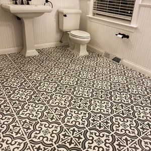 May include: A bathroom with a white pedestal sink, a white toilet, and a black and white patterned tile floor.
