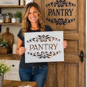 May include: A rectangular white stencil featuring the word PANTRY in a serif font, flanked by ornate, symmetrical scrollwork designs above and below the text. The stencil is made of a thin, flexible material designed for painting signs.
