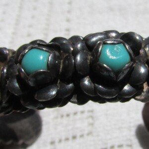 May include: A silver bracelet with turquoise stones set in a floral design.