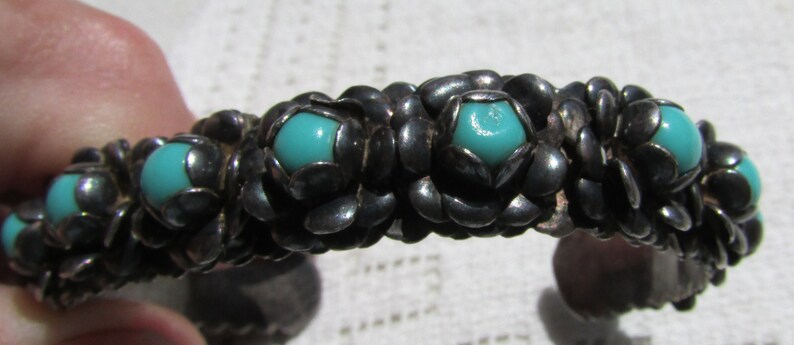 May include: A silver bracelet with turquoise stones set in a floral design.
