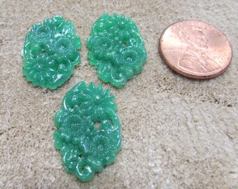 May include: Three green jade oval-shaped buttons with intricate floral designs. The buttons are approximately the size of a US penny.