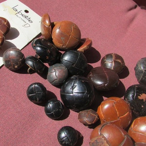 May include: A collection of round, brown and black buttons with a woven-look surface texture. Some buttons are loose, while others are attached to a white cardboard backing labeled la petite BUTTONS 30-3/4 5 ON 4612.