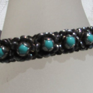 May include: A silver bracelet with turquoise stones set in a floral design.