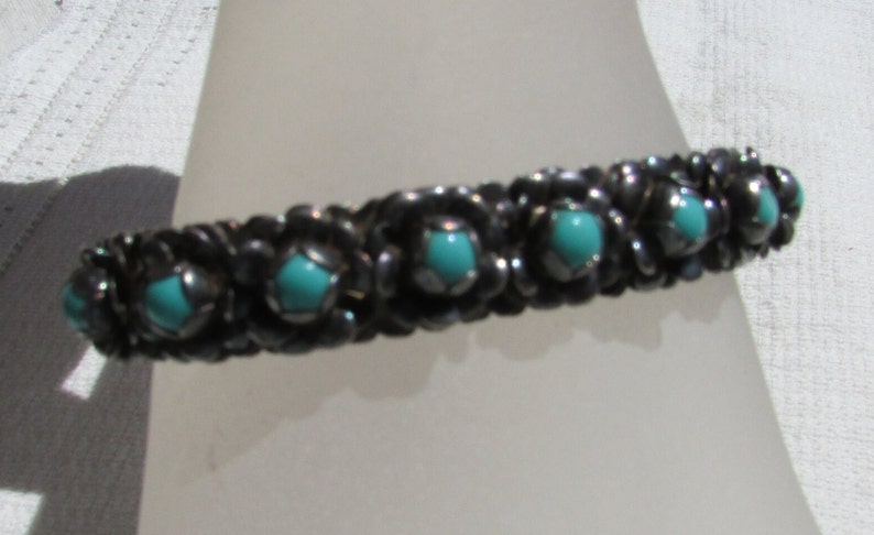 May include: A silver bracelet with turquoise stones set in a floral design.