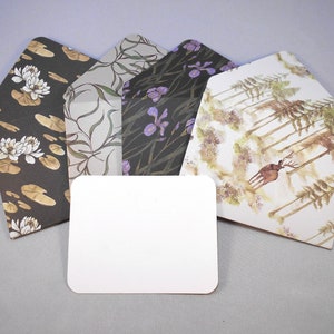 May include: Four patterned envelopes with a blank white card in the center. The envelopes feature different nature-inspired designs, including water lilies, irises, and a forest scene with a deer.