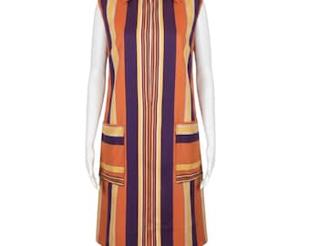 May include: A sleeveless knee-length dress featuring a vertical striped pattern in shades of orange, purple, and yellow. The garment includes a full-length front zip closure, a pointed collar, and two large patch pockets on the front hips.