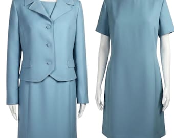 May include: A light blue two-piece suit consisting of a long-sleeved jacket with three buttons and a matching knee-length skirt, displayed alongside a separate light blue short-sleeved dress with a round neckline and a straight-cut silhouette.