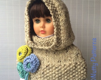 Può includere: Una sciarpa con cappuccio in maglia beige con un grande ricamo floreale in tonalità blu, verde e giallo. La sciarpa è indossata da una bambola con i capelli castani e gli occhi azzurri.