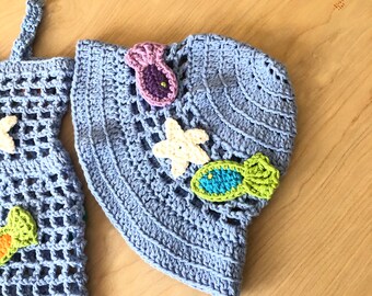May include: A light blue crocheted sun hat with a white crocheted starfish, a purple crocheted seashell, and a green crocheted fish.