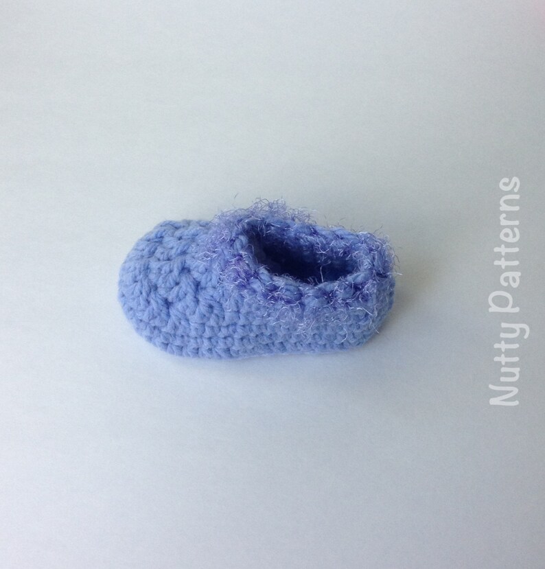May include: A pair of light blue crocheted baby booties with a fuzzy trim around the opening.