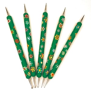 May include: Five green dotting tools with floral designs in red, yellow, and white. The tools have metal tips and are arranged on a white background. These tools are used for nail art and crafts.