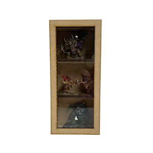 May include: A wooden display case with three shelves, each containing a painted miniature figure. The top shelf features a green figure with a purple flower, the middle shelf has two figures, one red and one orange, and the bottom shelf has a blue figure.