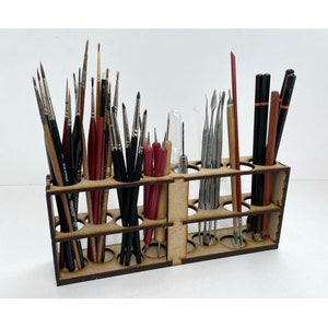 May include: A wooden stand with 20 slots for holding paint brushes and tools. The stand is made of light brown wood and has a natural finish. The stand is filled with a variety of brushes and tools, including some with red and black handles.