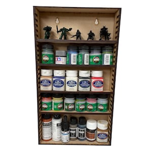 Peut inclure: Une étagère en bois à cinq niveaux, chaque niveau étant rempli de rangées de petits flacons de peinture. L'étagère supérieure présente des figurines miniatures peintes en vert, noir et gris.