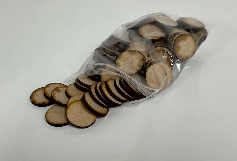 May include: A clear plastic bag filled with a large quantity of round, wooden craft circles. The circles are light brown with dark brown edges.